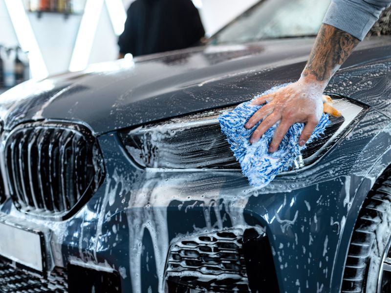 Microfiber mitt being used to wash and detail BMW headlight